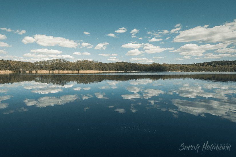 still lake image with puffy clouds and clear blue sky