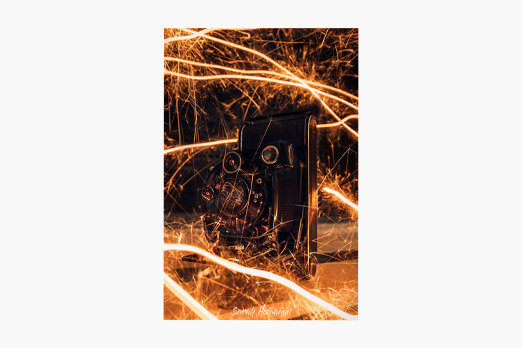 Old vintage camera placed on wood with fire-looking sparklers around it